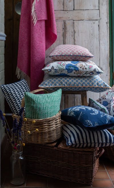 Kitty-Holmes-Colourful-cushions-piled-in-baskets-in-front-of-wood-door